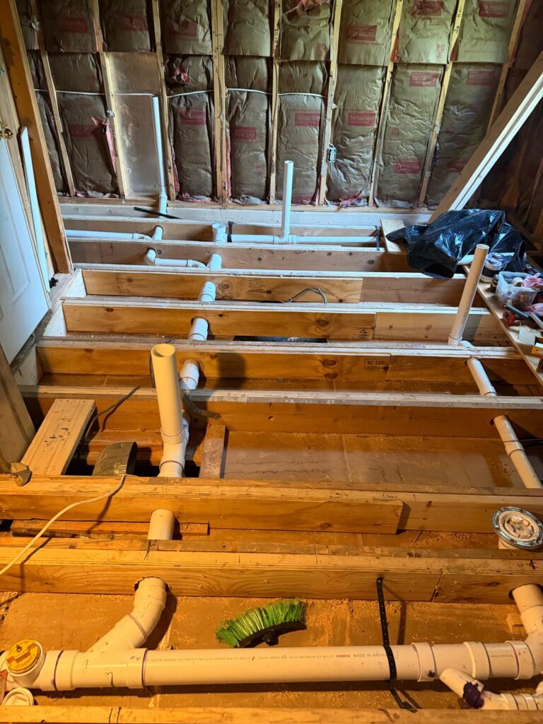 Bathroom rough-in plumbing installation with PVC drain and water lines during home remodeling